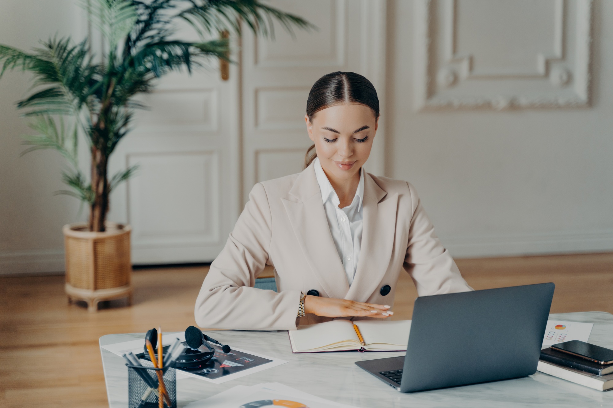 Concentrated bussiness woman sitting by desk in front of laptop